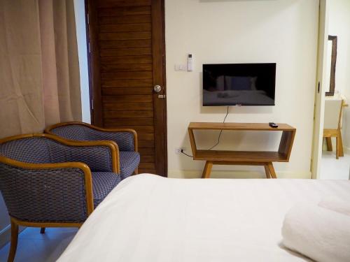 a bedroom with a bed and a table and a tv at Baan Dan Ta Wan Nuea in Chiang Mai