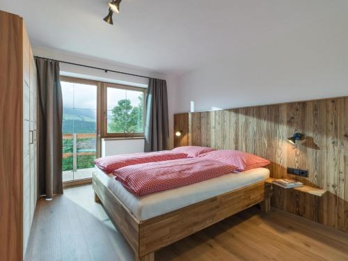 1 dormitorio con cama y ventana grande en BERGappartement KINK, en Hopfgarten im Brixental
