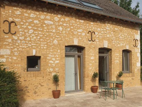 un edificio de ladrillo con una mesa y sillas delante de él en Chambres d'hôtes de La Vallée, en Mansigné