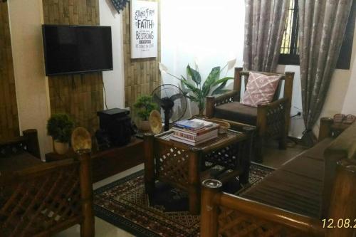 uma sala de estar com um sofá e uma TV em A Filipino Rustic Style Duplex in Rosario, Cavite UNIT A em Rosario