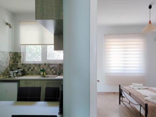 eine Küche mit einem Tisch und einem Fenster mit Jalousien in der Unterkunft Akrotopi Apartments & Studios in Tolo