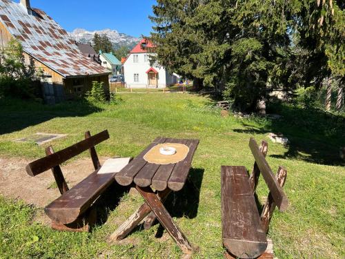 a wooden picnic table and bench in a field at Dormire Apartmans in Žabljak