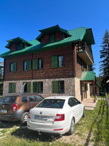 a house with two cars parked in front of it at Dormire Apartmans in Žabljak