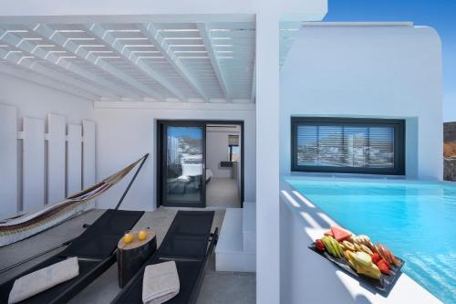 a swimming pool with a hammock next to a house at Deliades Hotel in Ornos