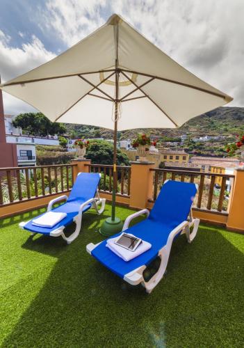 two blue chairs and an umbrella on a balcony at Hotel Emblemático San Marcos in Icod de los Vinos