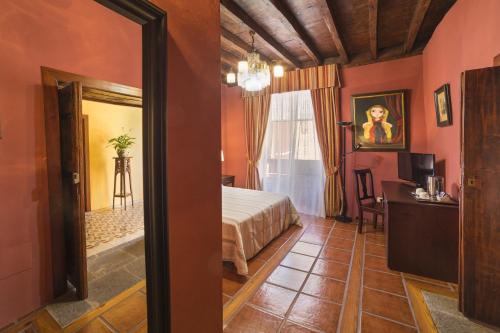 a bedroom with a bed and a desk and a mirror at Hotel Emblemático San Marcos in Icod de los Vinos