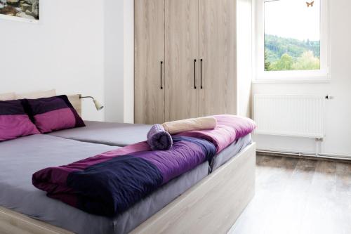 a bed with a purple blanket on it in a room at penzion Valentino in Bedřichov