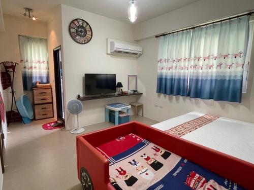 a bedroom with a bed and a tv and a clock at 芹菜芋頭親子民宿 in Taitung City