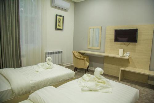 a hotel room with two beds with towels on them at South Hotel Tashkent in Tashkent