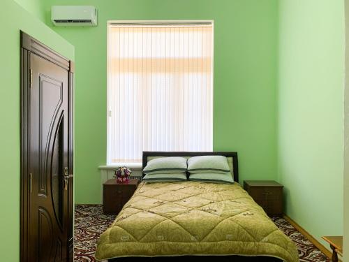 a bedroom with a bed with green walls and a window at Safar Guest House in Samarkand