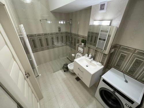 uma casa de banho com um chuveiro, um lavatório e uma máquina de lavar roupa em Mamaia Beach LuxyMar 3 Apartment em Mamaia