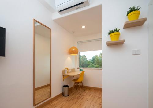 a bathroom with a mirror and a desk with a chair at Bloom Hotel - Brookefield in Bengaluru