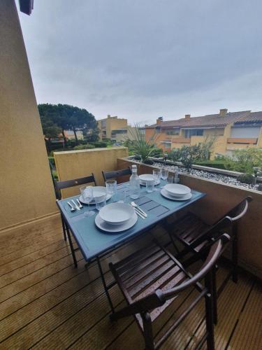 une table bleue avec des assiettes et des verres sur un balcon dans l'établissement Appt 4 pers, refait à neuf 2022, terrasse, parking, au Cap d'Agde