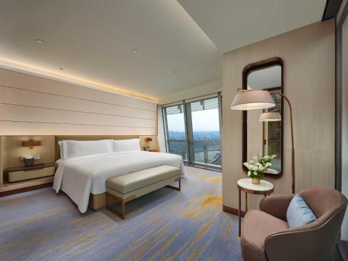 a hotel room with a bed and a chair at InterContinental Chongqing Raffles City by IHG in Chongqing