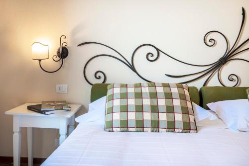a bed with a plaid pillow and a table with a lamp at Hotel Borgo Di Cortefreda - Place of Charme in Tavarnelle in Val di Pesa