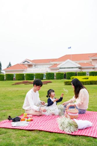a group of people sitting on a picnic blanket at Xiamen C&D Hotel-Free Welcome Snacks-Oasis Garden in Xiamen