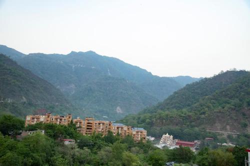 a city in front of mountains with buildings and trees at Hotel Dream Inn in Rishīkesh