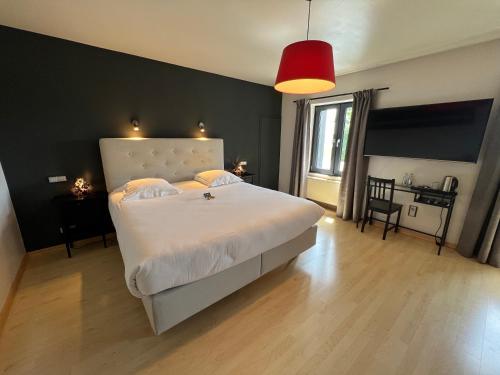 a bedroom with a large white bed and a red lamp at Hôtel Restaurant Lamy in Troisvierges
