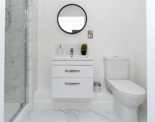 ein weißes Bad mit einem WC und einem Spiegel in der Unterkunft Beautiful Apartments in Kings Lynn Town Centre in Kings Lynn