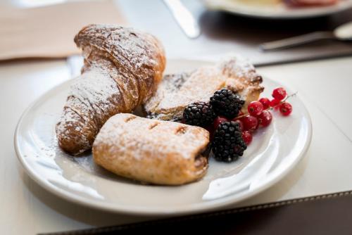 a white plate with pastries and berries on a table at Hotel Borgo Di Cortefreda - Place of Charme in Tavarnelle in Val di Pesa