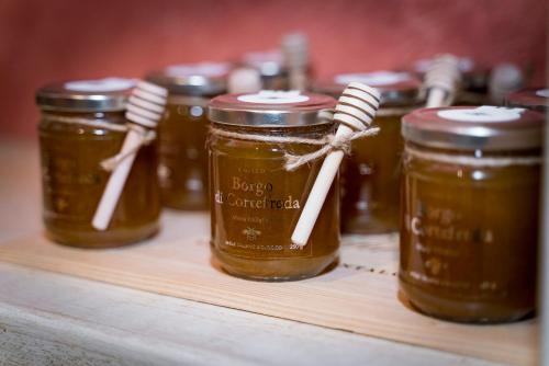 a group of jars of honey on a wooden shelf at Hotel Borgo Di Cortefreda - Place of Charme in Tavarnelle in Val di Pesa