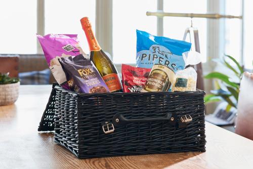 a basket of wine and snacks on a table at The Spa Chalet Scarborough Hot tub, pool, gym, beach location in Scarborough