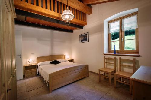 a bedroom with a bed and a desk and a window at La Marmote Albergo Diffuso di Paluzza Rio Bavous in Paluzza