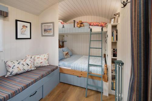 a small bedroom with bunk beds and a bench at Cow Parsley Shepherd's Hut in Berwick-Upon-Tweed