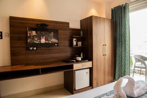 a bedroom with a desk and a tv on a wall at Hotel Dream Inn in Rishīkesh