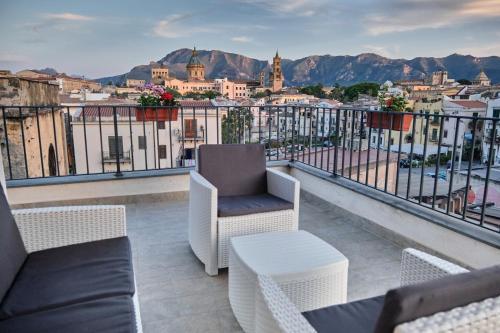 a balcony with chairs and a view of a city at Mercede Rooms in Palermo