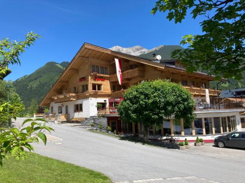a large wooden building with a tree in front of it at Aparthotel Tyrol in Lermoos