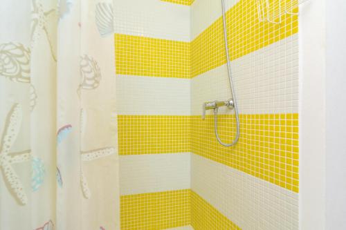 a bathroom with a shower with yellow and white tiles at Ca na Clar in Sa Ràpita
