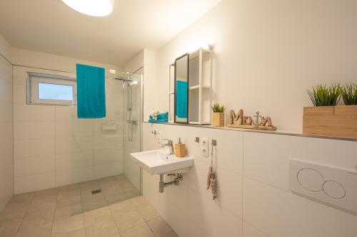 ein weißes Bad mit einem Waschbecken und einer Dusche in der Unterkunft Wohnen am Südstrand - Ferienwohnung 0 7 in Wyk auf Föhr