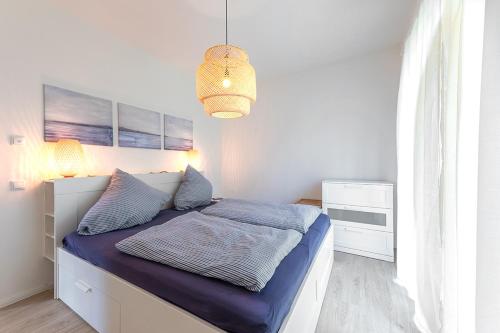 a bedroom with a bed with blue sheets and a chandelier at Wohnen am Südstrand - Ferienwohnung 0 1 in Wyk auf Föhr