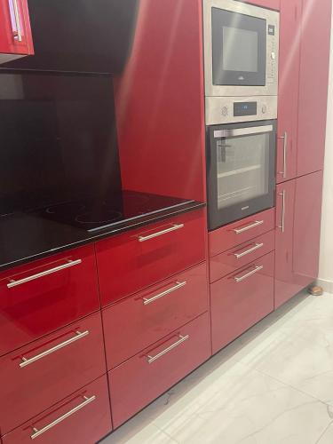 - une cuisine rouge équipée d'un four micro-ondes et d'une cuisinière dans l'établissement CALME, EMPLACEMENT PARFAIT, 15 min PARIS, à Saint-Maur-des-Fossés