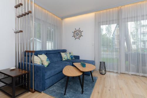 a living room with a blue couch and a table at Horizon Park Apartment by Renters in Dziwnówek