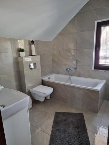 a bathroom with a tub and a toilet and a sink at Dwie Mewy in Pobierowo