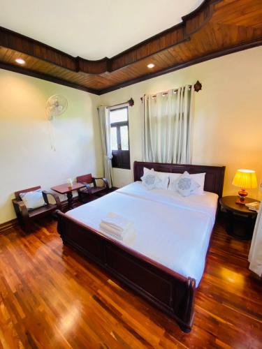 a bedroom with a large bed and a wooden floor at Luang Prabang Maison Vongprachan & Travel in Luang Prabang