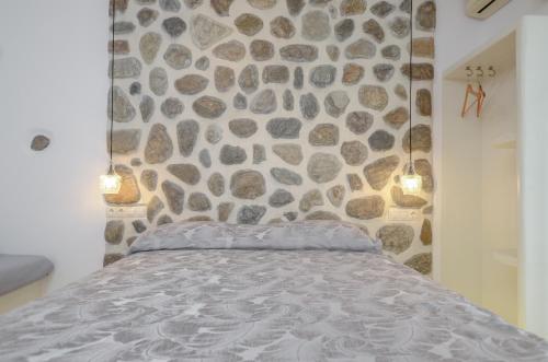 a bedroom with a stone wall and a bed at simos luxury apartments in Naxos Chora
