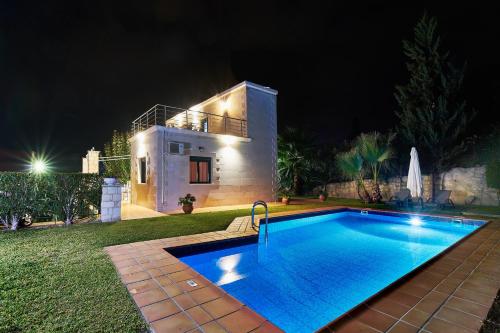 a swimming pool in front of a house at night at Villa Elia by PosarelliVillas in Vryses