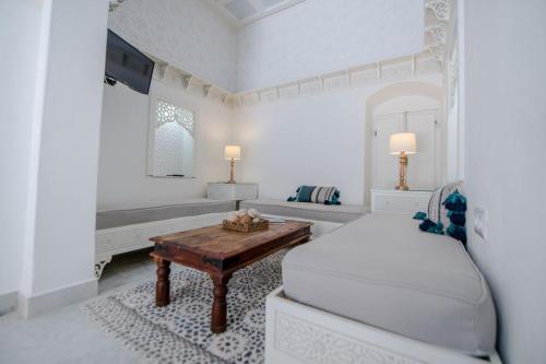 a white bedroom with a bed and a table at Dar Benti in Monastir