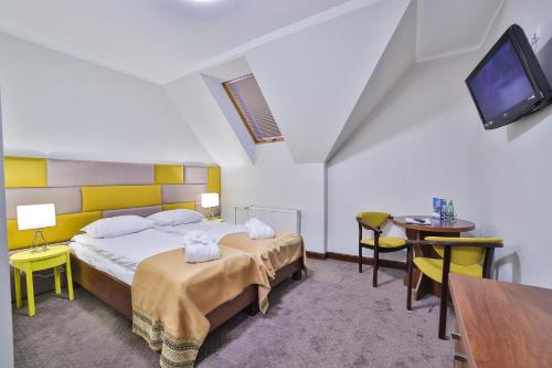 a bedroom with a bed and a tv and a table at Hotel Kompleks Beskid z basenem i stokiem narciarskim - blisko Babiej Góry in Spytkowice