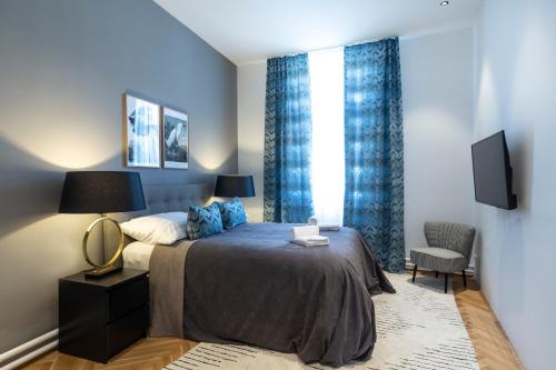 a bedroom with a bed with blue curtains and a tv at sgrafit apartments in Retz