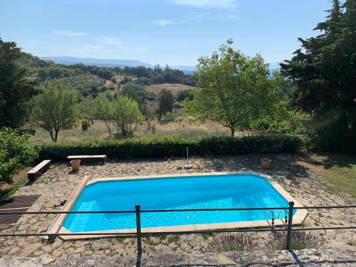 une piscine bleue dans une cour arborée dans l'établissement Maison Zouz, à Murs