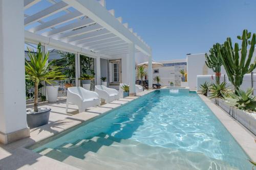 a swimming pool with chairs and a pergola at Dar Benti in Monastir