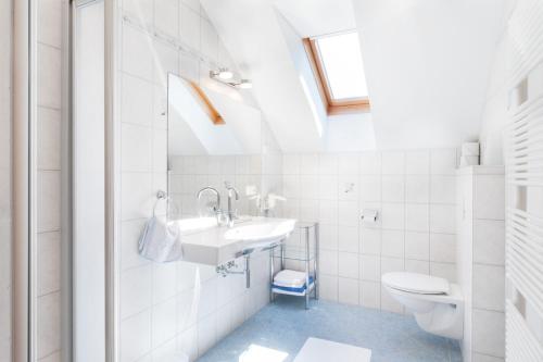 a white bathroom with a sink and a toilet at Haus Wolfgangsee in Sankt Gilgen