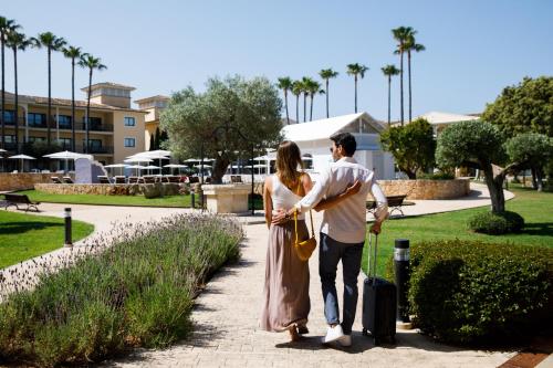 a man and a woman standing in a park with a suitcase at CM Mallorca Palace - Only Adults in Sa Coma