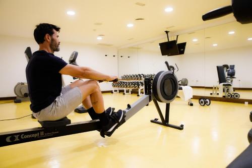 a man sitting on a bench in a gym at CM Mallorca Palace - Only Adults in Sa Coma