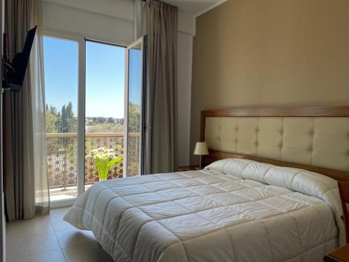 a bedroom with a large bed and a large window at Hotel Posidonia in Porto Cesareo