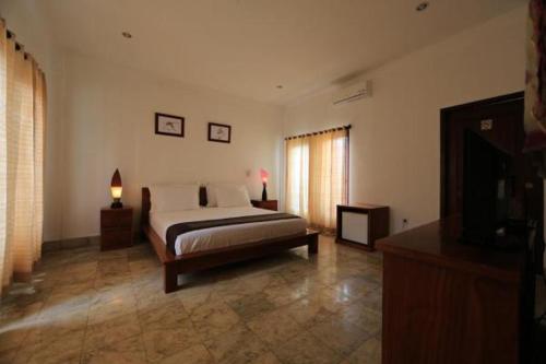 a bedroom with a bed and a television in it at Aaliku Bungalows in Gili Trawangan